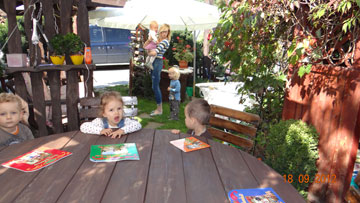 Dzieci siedzą przy stole i mają przed sobą książeczki